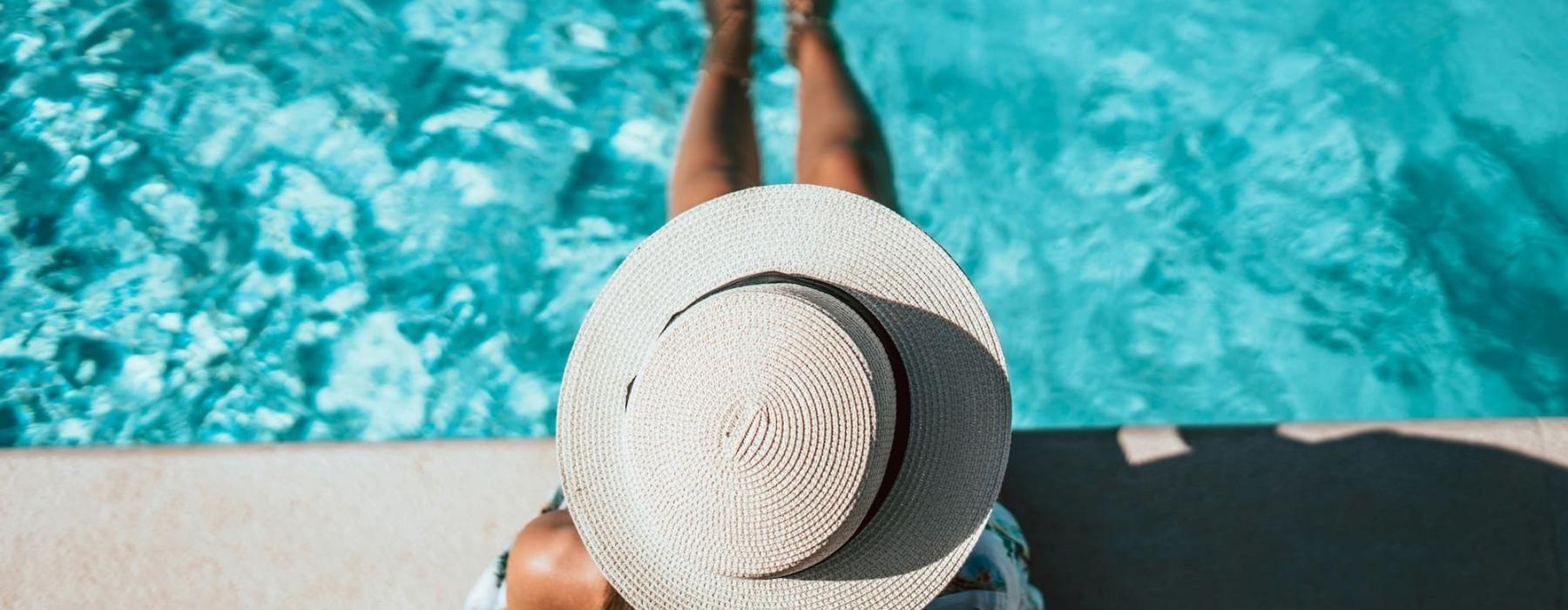 a person wearing a hat sitting next to a pool